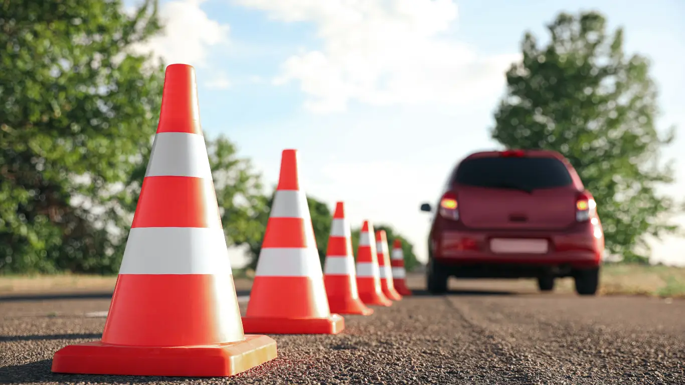 Learner driver practicing K53 parking by reversing a car between orange cones during driving lessons in Durban